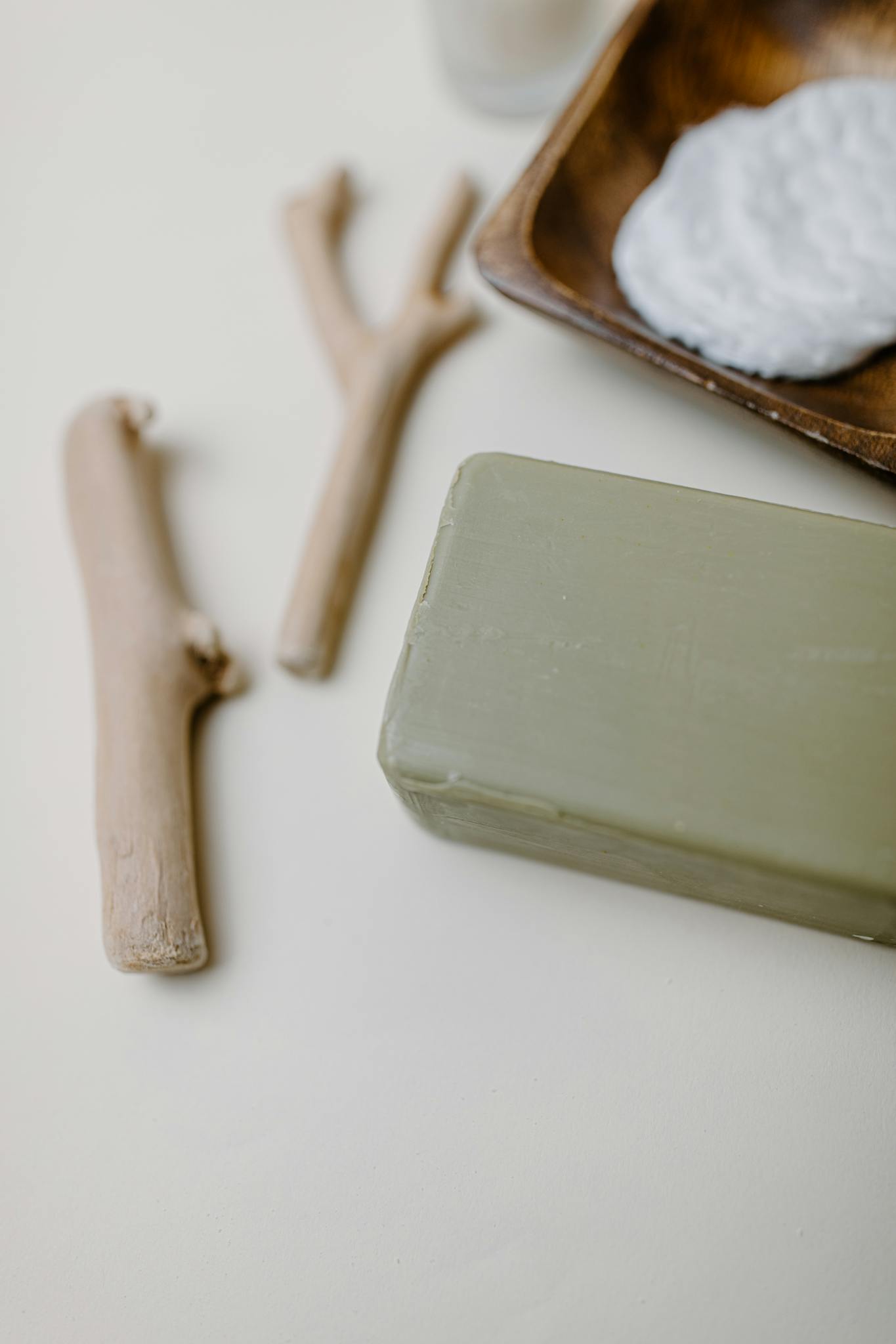 A minimalist arrangement of natural soap, cotton pads, and wooden elements for skincare routine.